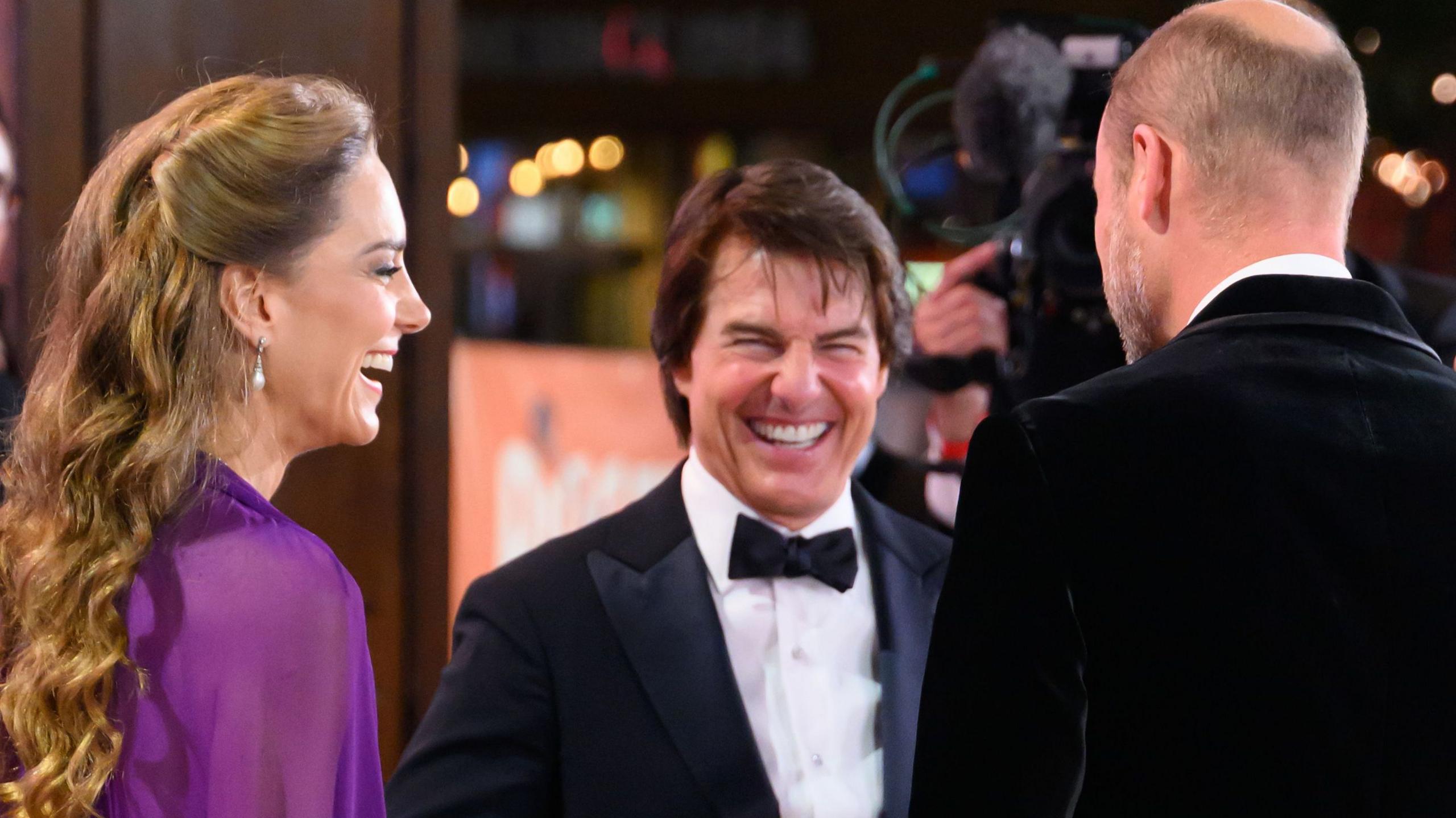 The Prince and Princess of Wales speaking to Tom Cruise, all in formal dress and laughing
