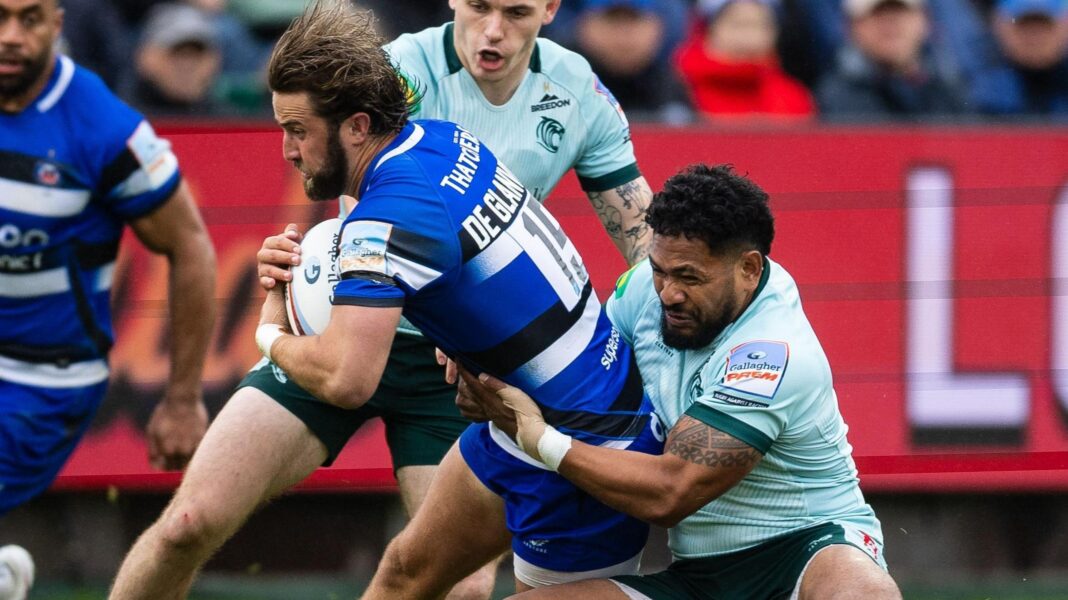Tom De Glanville is tackled around the waist by a Leicester player while holding the ball, in match action from Bath v Leicester in June 2026