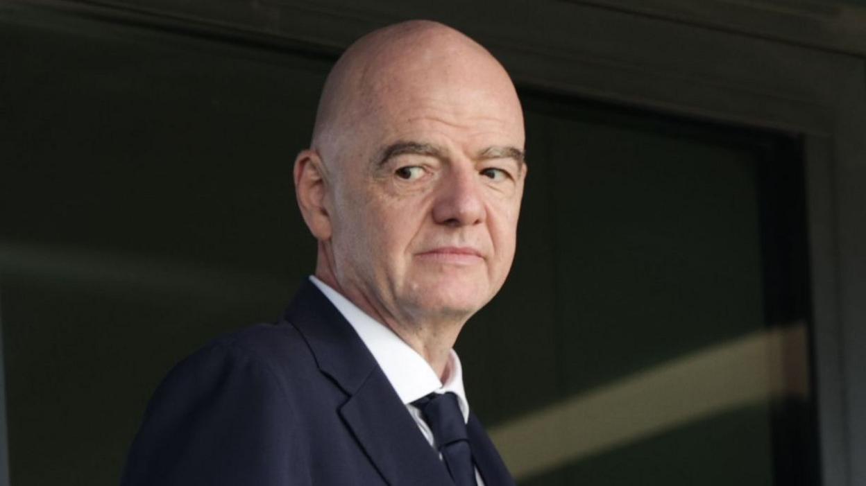 Head and shoulders view of Gianni Infantino looking to his right, as he wears dark jacket and tie and a white shirt
