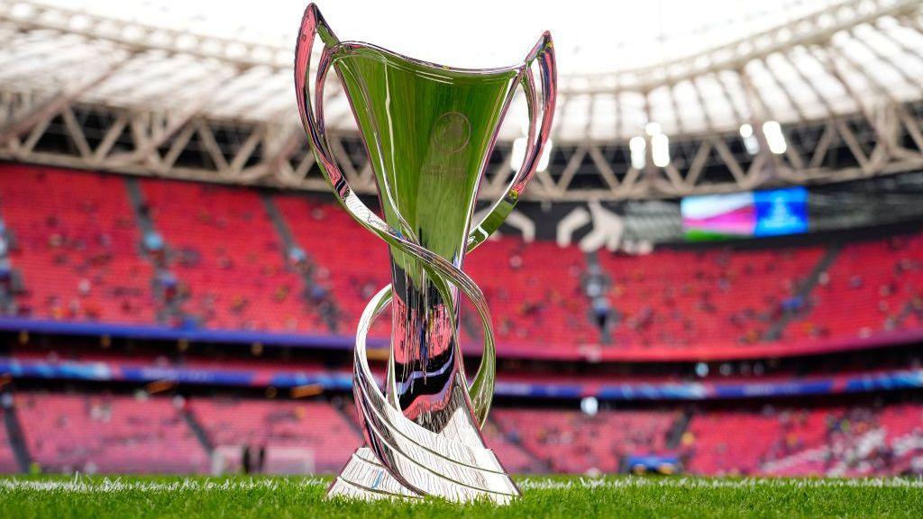 A close-up picture of the Women's Champions League trophy in an empty stadium with red seats visible in the background