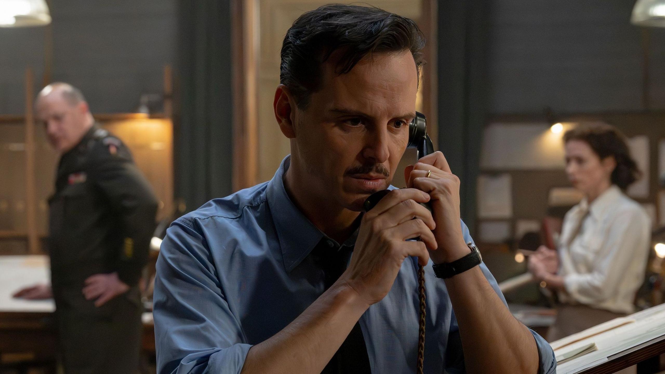 Andrew Scott in a wartime shirt with a small moustache and clipped, short hair - he is on the phone on the set of the film, looking tense