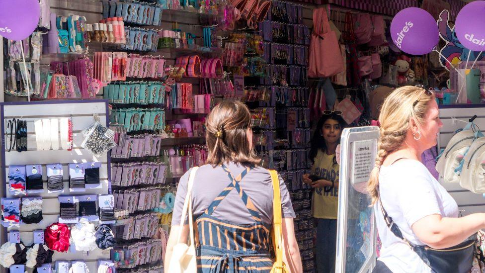 Shoppers inside a Claire's store with rows of merchandise