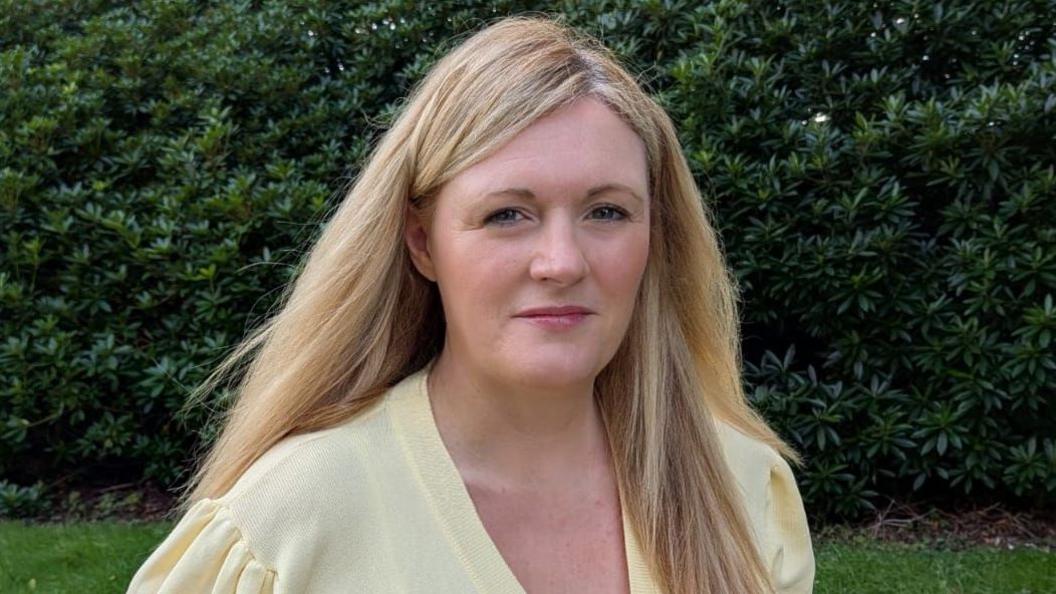 Shows a woman with blonde hair and wearing a yellow top