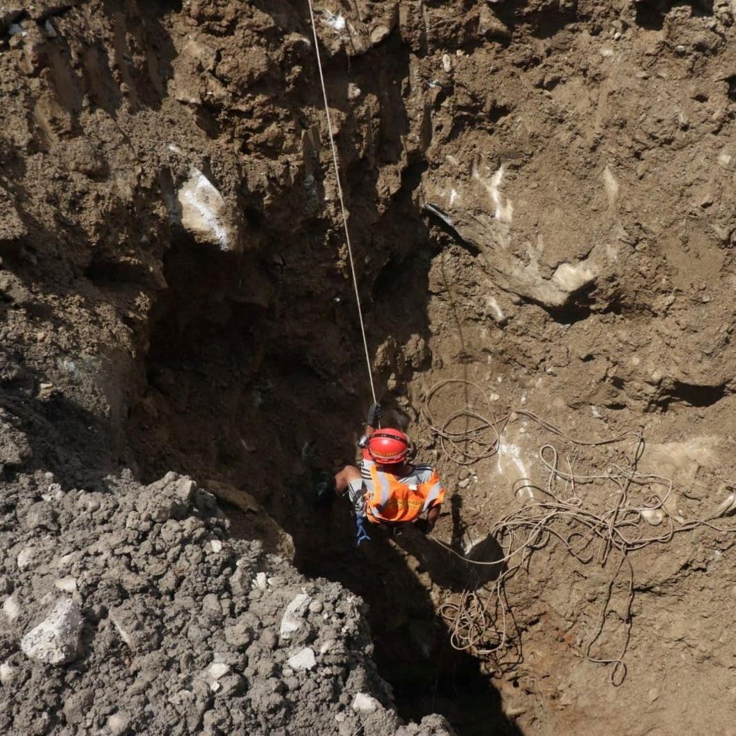 A rescue worker lowering themselves into a hole ata hydropower site