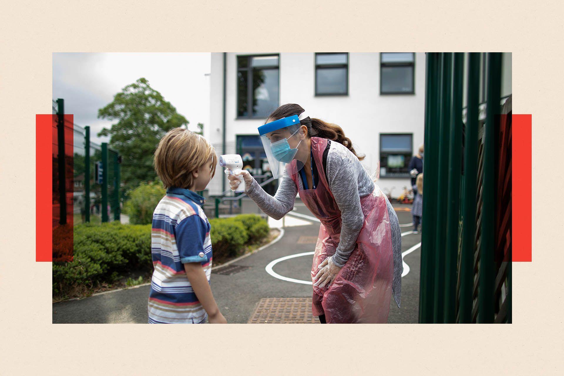 A teacher in a mask checks a child's temperature in a playground