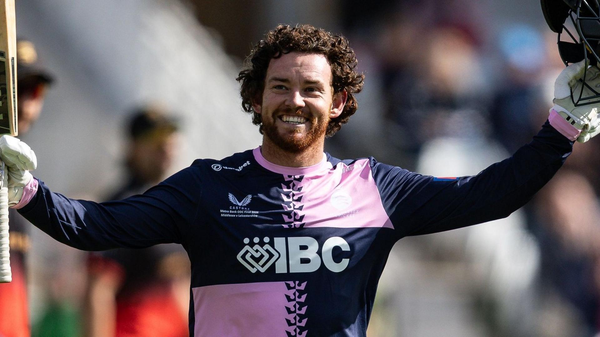 Ryan Higgins celebrates scoring a century by raising his bat and helmet
