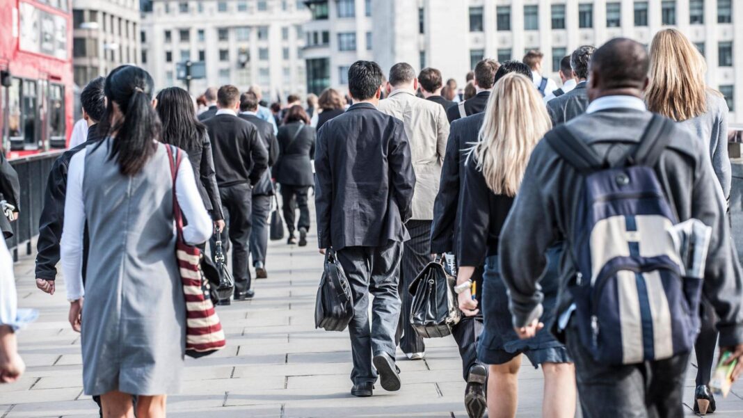 Commuters walking along a pavement in a city