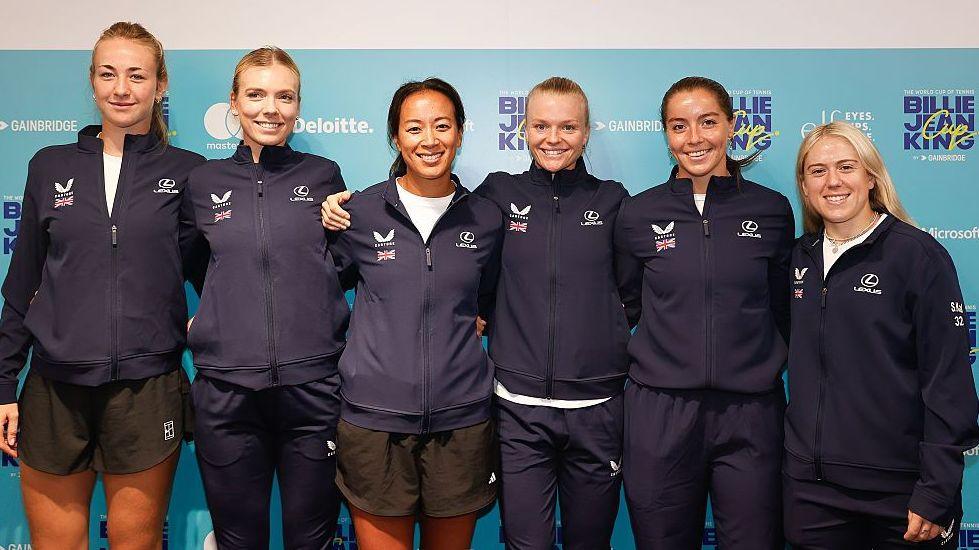 Mika Stojsavljevic, Katie Boulter, Anne Keothavong, Harriet Dart, Jodie Burrage and Sonay Kartal pose for a photograph with arms around each other, all wearing zip-up blue team tracksuit tops