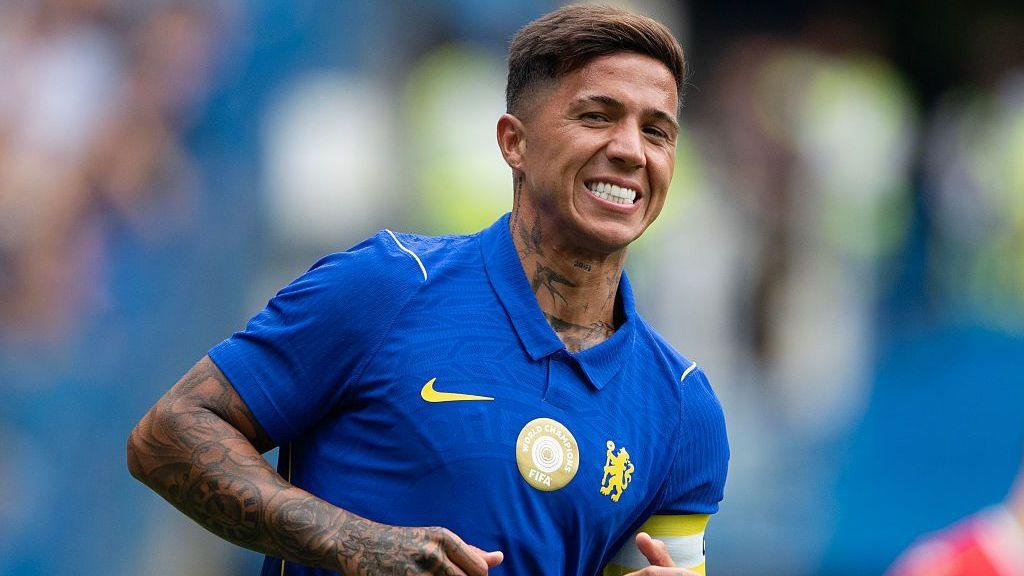 Enzo Fernandez smiles and is wearing a blue Chelsea shirt