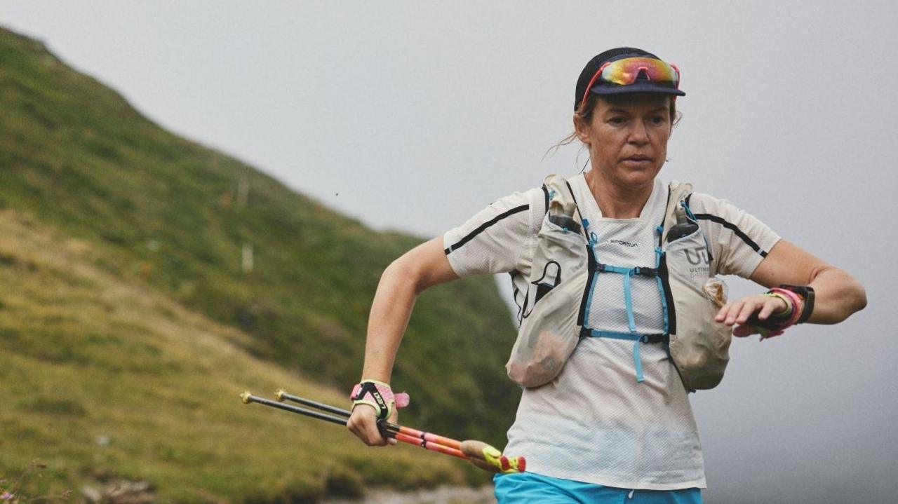 Sophie Woods running, carrying walking poles
