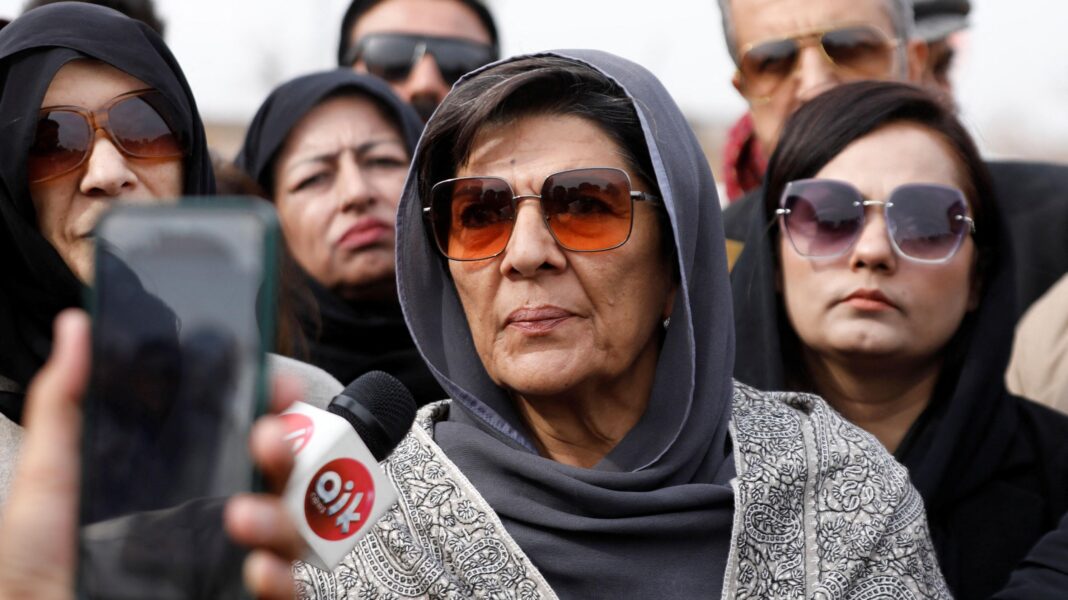 Sister of Pakistan’s ex-PM Imran Khan arrested Aleema Khanum wears a grey head covering and sunglasses as she speaks into a news microphone. There are other women standing behind her.