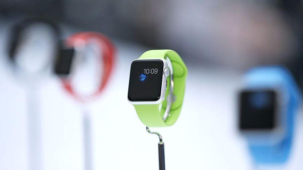 The first edition Apple Watch, with a lime green band, shown on a display alongside other brightly coloured Apple Watches in 2014