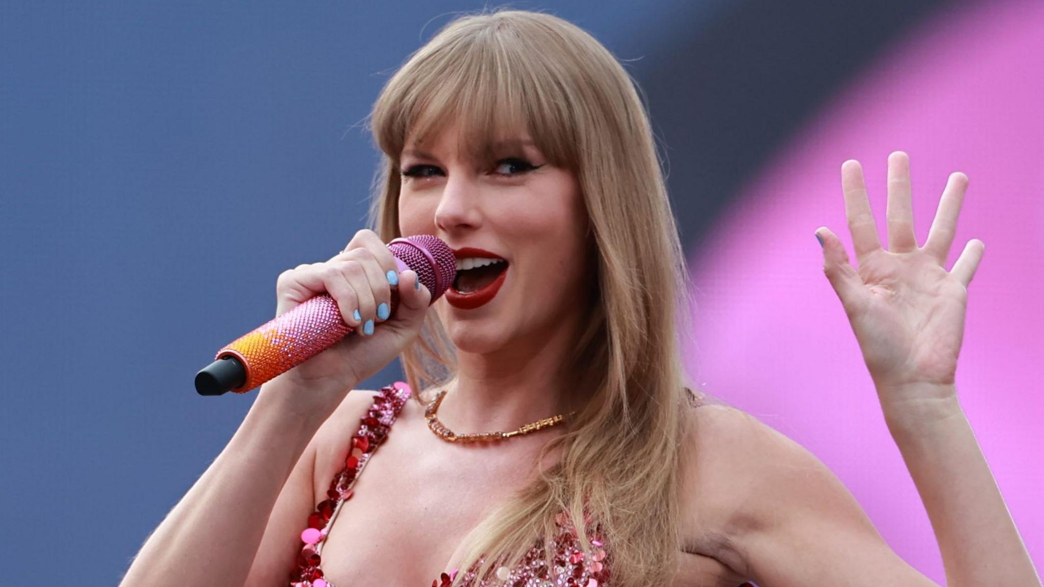 Taylor Swift waving while performing on stage at the Aviva Stadium in Dublin, during the Eras Tour in 2025