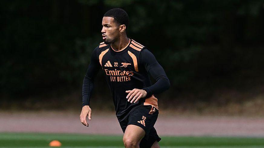 Ethan Nwaneri, wearing a black shirt and shorts, dribbles a ball during an Arsenal training session
