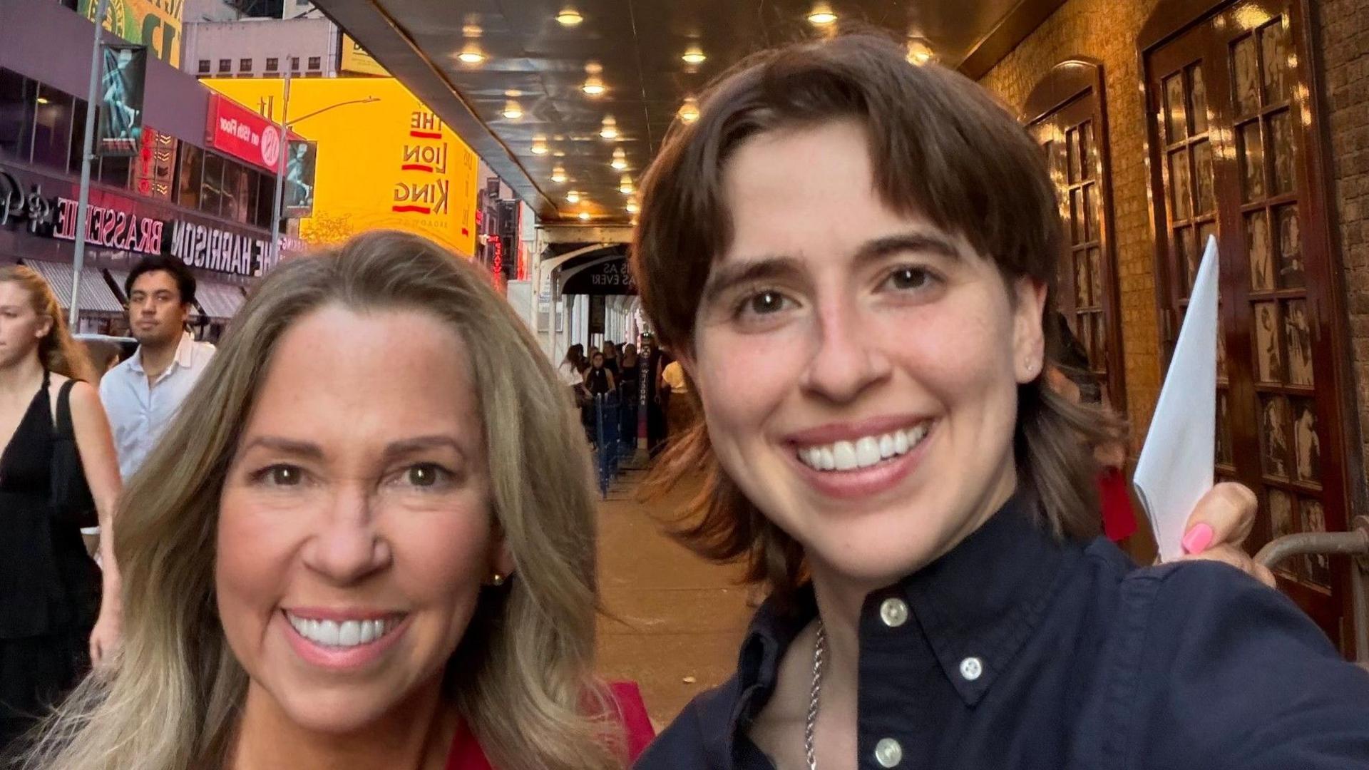 Sealy Sikes (right) with her mum Tammy (left) on Broadway. Tammy has blonde hair and wears a pink dress, Sealy wears a blue shirt with a silver chain and has short brown shoulder length hair with a fringe