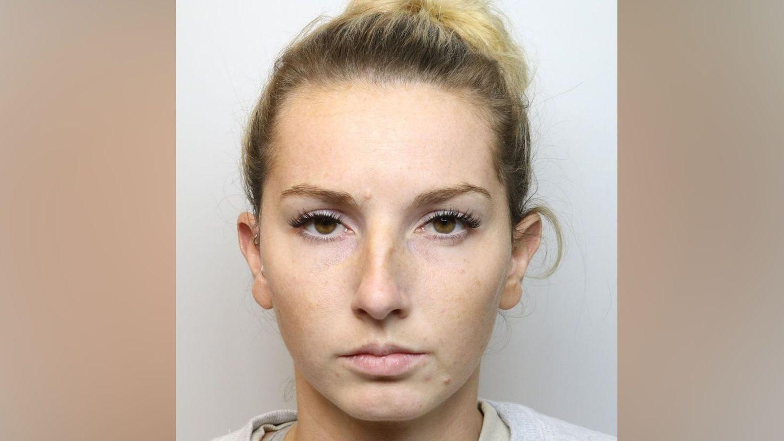 A mugshot of Bronwen James, she has blonde died hair tied in a bun and appears to be in her late twenties or early thirties, she is wearing a grey jumper