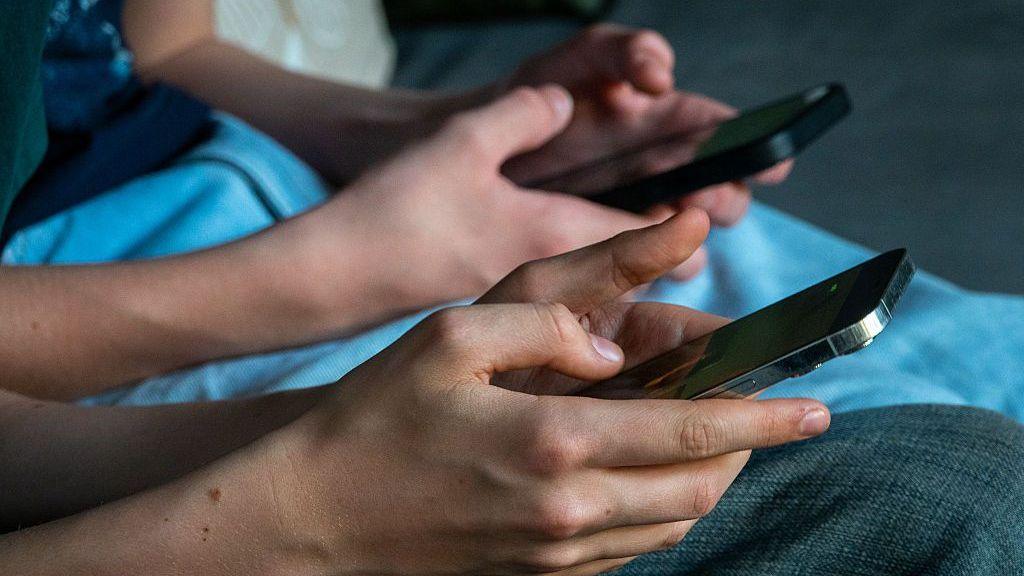 A close-up image of two people sitting together, using their smartphones