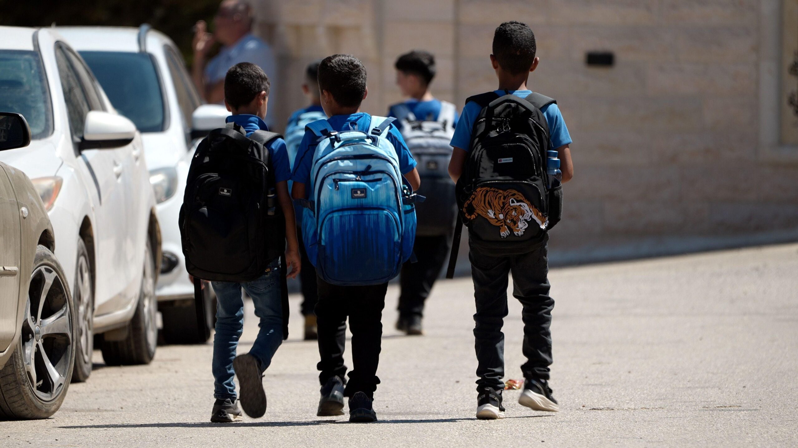 Palestinian kids walk to school. They are wearing blue school uniforms.