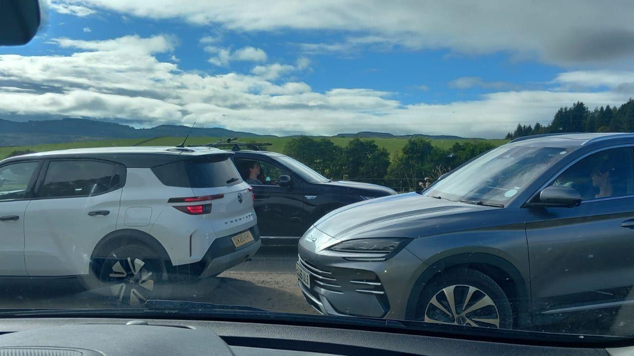 Three cars on the single-track road from the side.