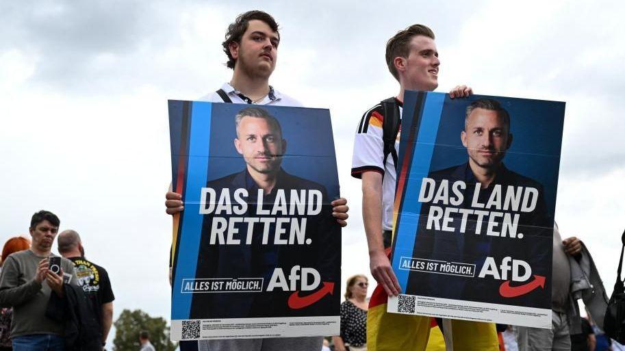 Supporters of the Alternative for Germany (AfD) party hold placards as they attend AfD top candidate Ulrich Siegmund's campaign event ahead of the upcoming Saxony-Anhalt state elections in Magdeburg, Germany