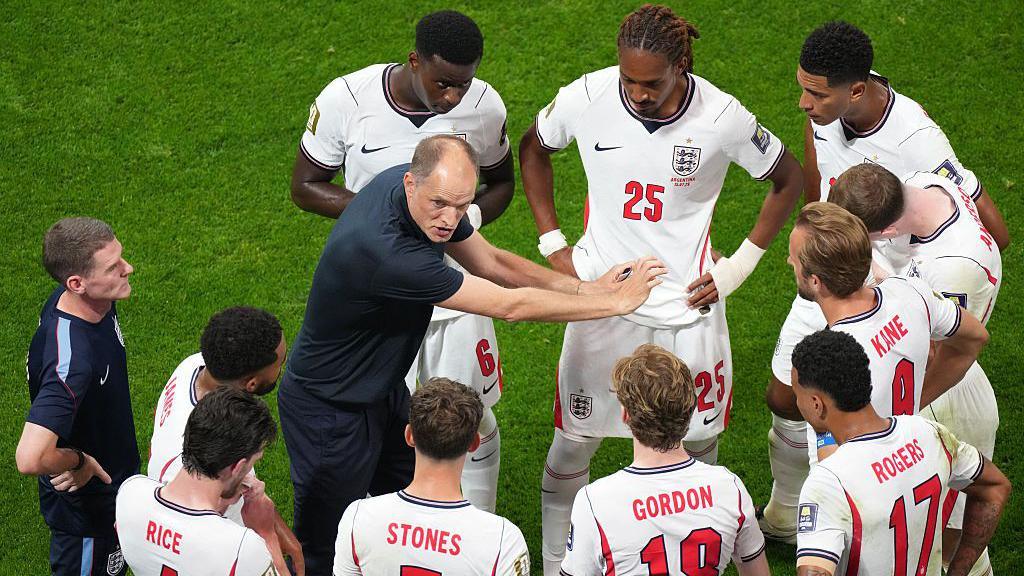Thomas Tuchel gesticulates by pushing his arms out while delivering a team talk to his England players