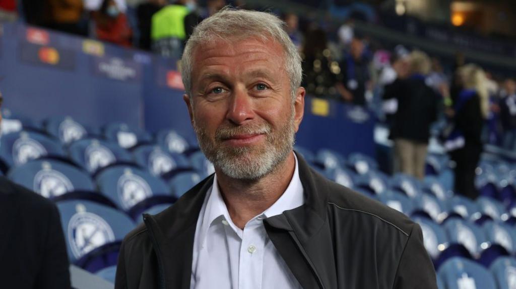 Former owner Roman Abramovich smiles while standing pitchside at Stamford Bridge ahead of a Chelsea match in the Uefa Champions League
