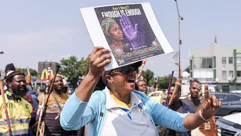 A woman holds up an anti-abuse poster as she joins a protest in South Africa