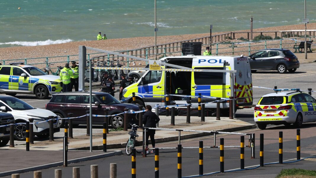 No criminality in death of three sisters who died in sea Police vehicles and officers in the Black Rock car park on Madeira Drive after the bodies of three women were recovered from the sea in Brighton. The car park is next to a pebble beach, where two more officers are standing in the distance.