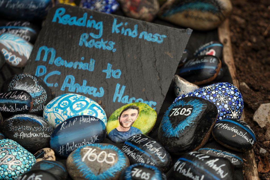 A pile of painted rocks with the name Andrew Harper on them and paintings of the officer.