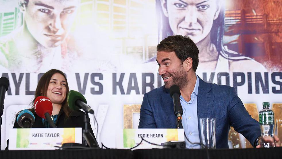 Katie Taylor and Eddie Hearn smile and laugh
