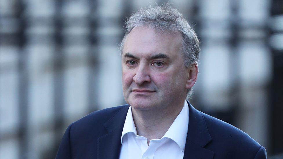 Lord Wormald has short grey hair, a dark-coloured jacket and a white shirt which has the top button open.