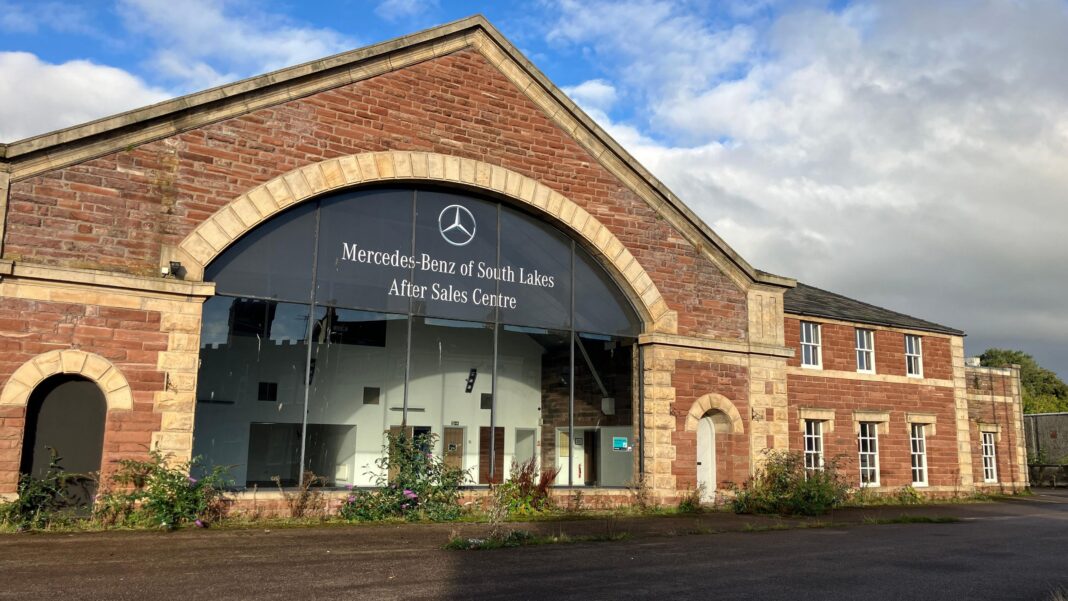 A large red sandstone building with a central arched glass frontage displaying the sign 