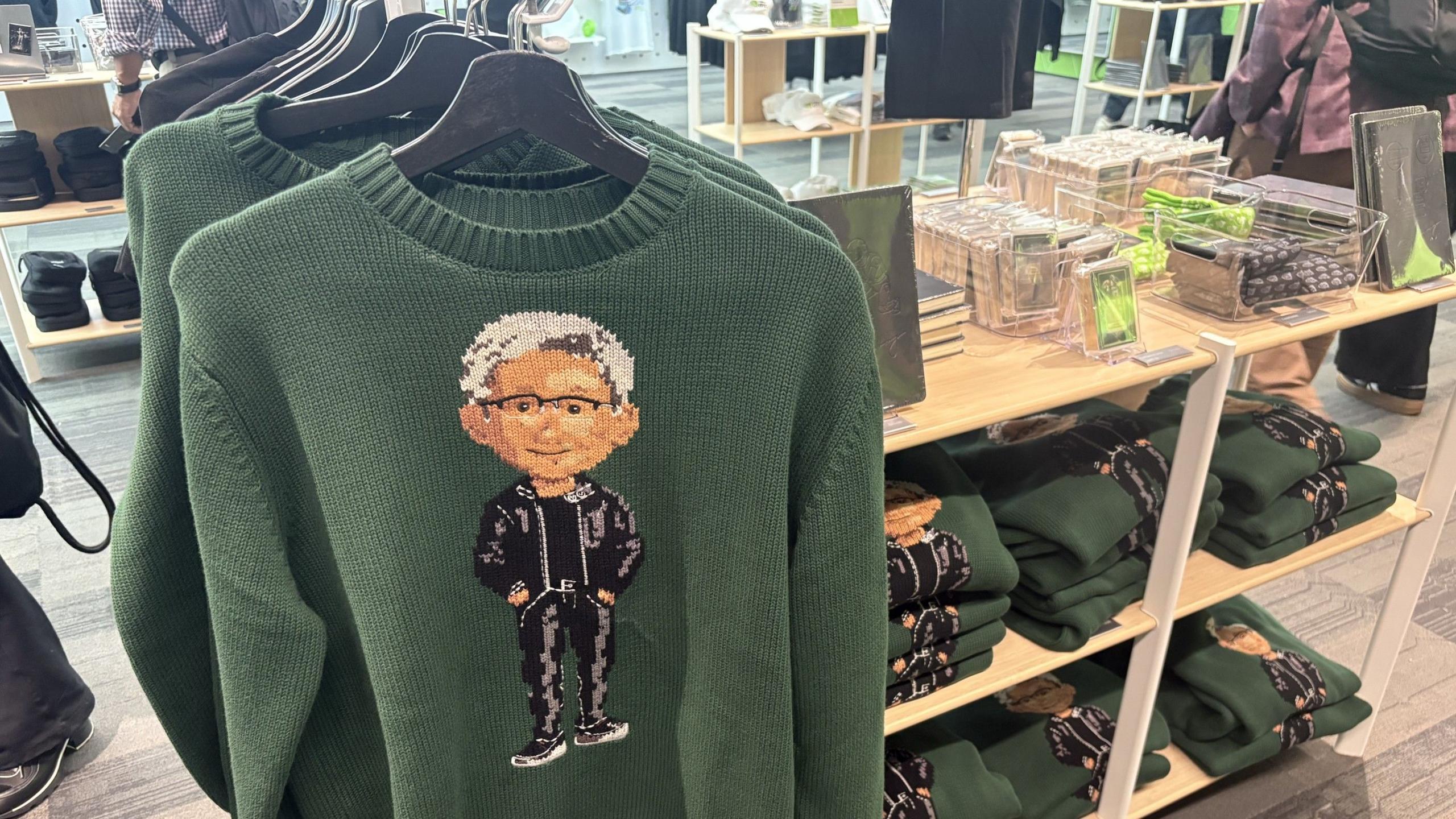 Green Nvidia jumpers with an image of the company's boss Jensen Huang on the front, hanging up on a store