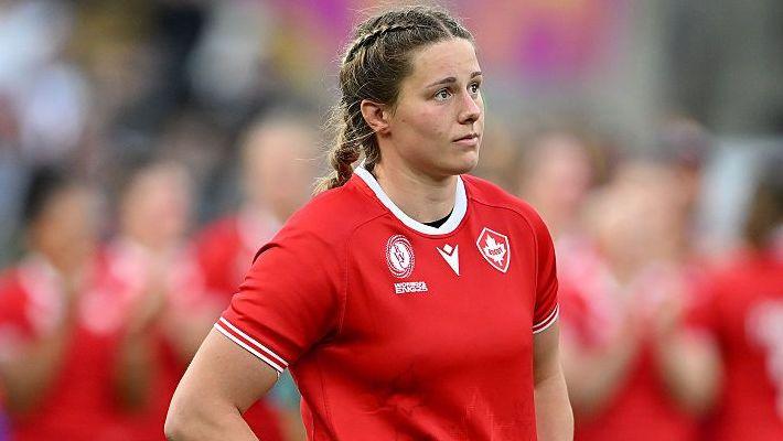 Sophie de Goede, in a red short-sleeved shirt, looking dejected after the 2025 World Cup final with blurred team-mates in the background