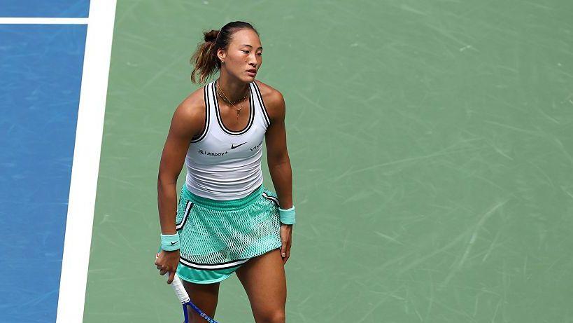 Zheng Qinwen, wearing a white vest and mint green shorts, looks dejected