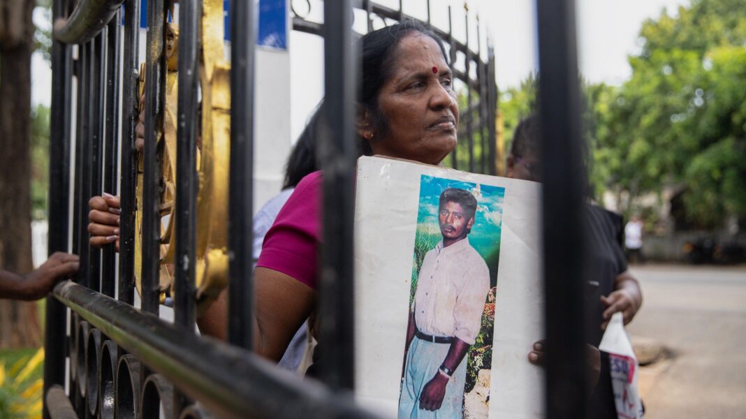 Workers came across human remains – and unearthed a mass grave of 572 people Suseela holds a photograph of her son, Gnanaseelan Ravi, she is seen through the bars on a fence.