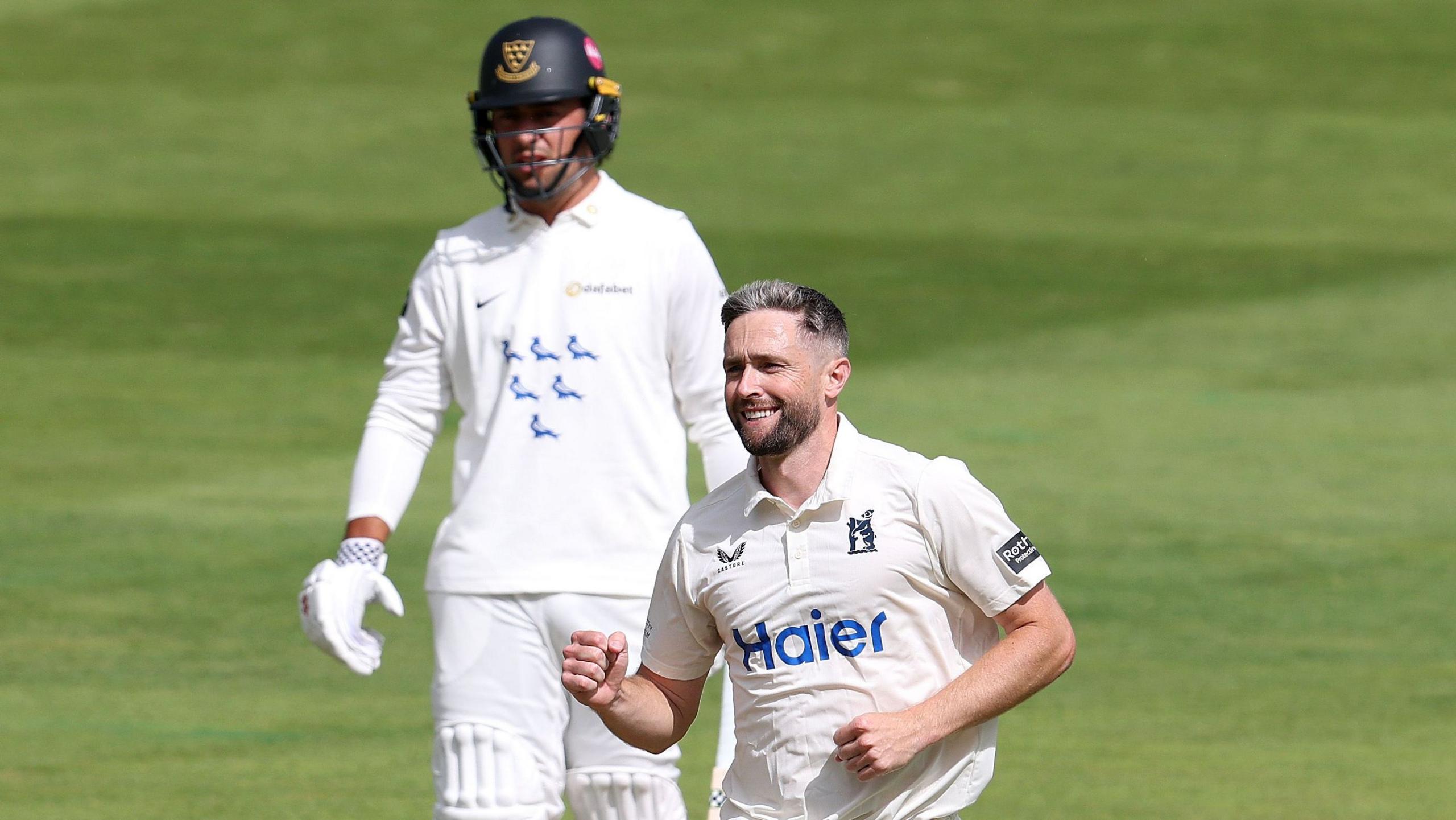 Chris Woakes celebrates taking a wicket with a Sussex batter stood at the non-striker's end behind him