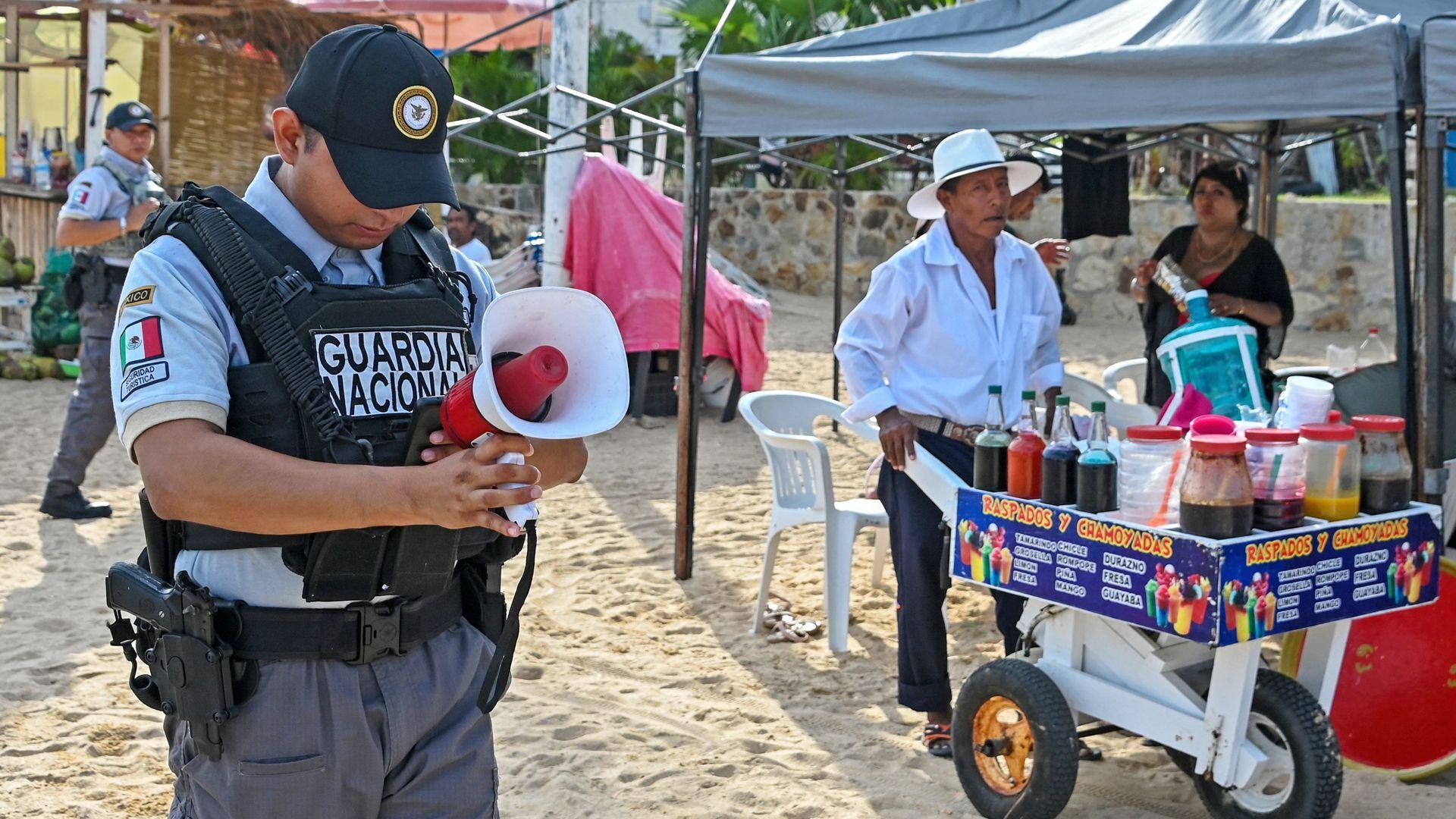 A member of the Mexican National Guard makes an announcement to residents and visitors about the approach of Hurricane Polo along a beach in Acapulco, Guerrero state, Mexico, on September 21, 2026.