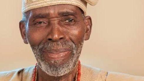 Nollywood actor Olu Jacobs dressed in brown  traditional Yoruba attire consisting of a baban riga and a hat