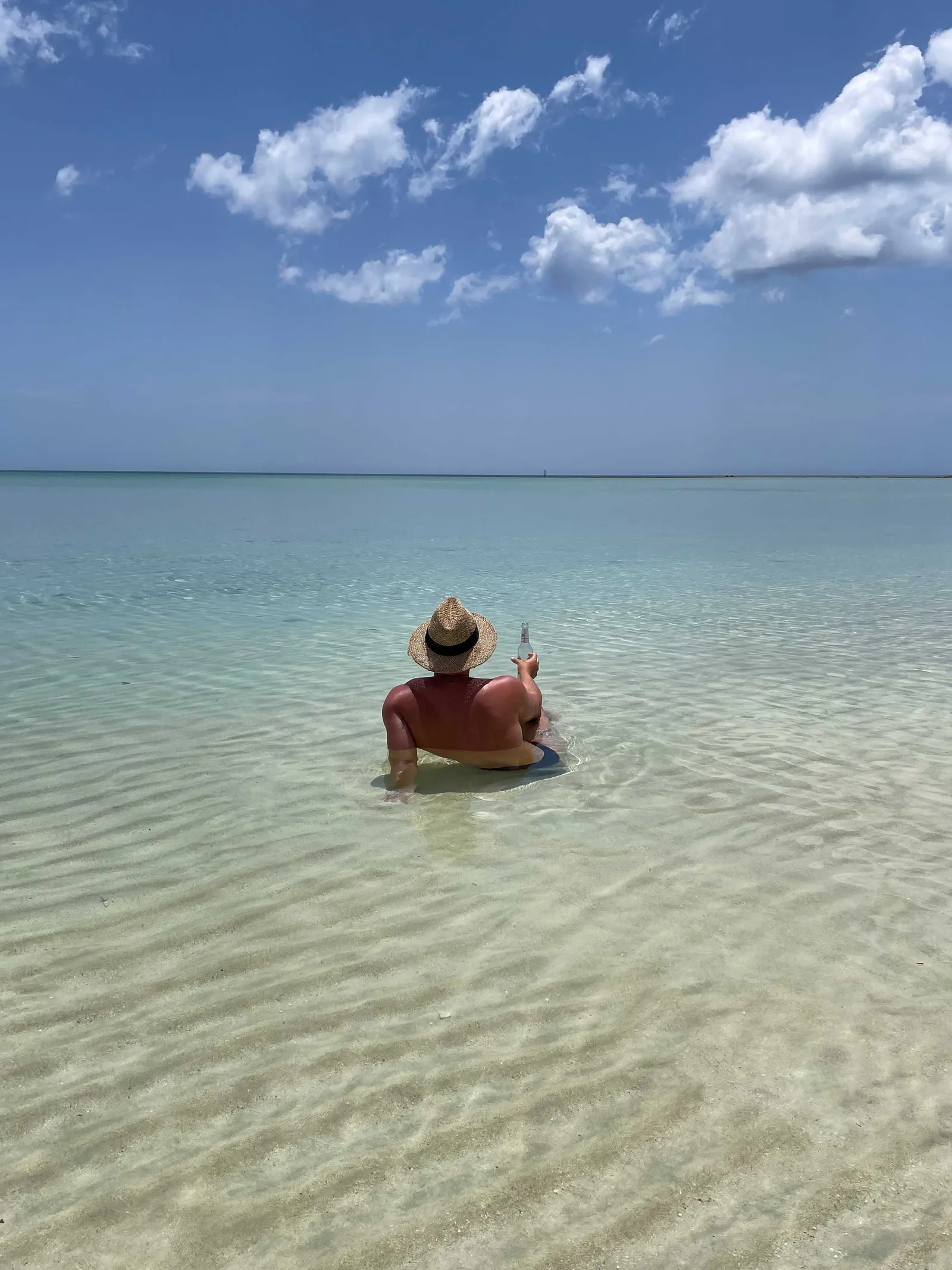 Image may contain Nature Outdoors Sky Horizon Fun Vacation Adult Person Sitting Clothing and Hat