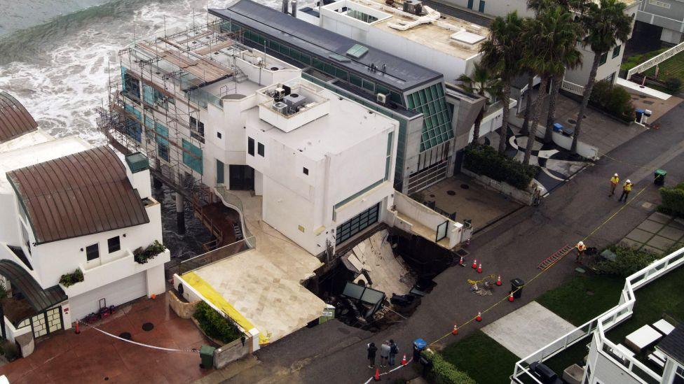 This aerial view shows a sinkhole on a street and driveway of a seaside home affected by large swells produced by Hurricane Marie in Malibu, California, on September 8, 2026. Hurricane Marie stayed well offshore of Southern California during Labor Day weekend but its large swells produced dangerous surf and rip currents, with waves reaching around 10 feet in some areas.