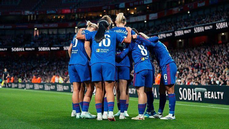 Manchester United players, in blue kit, gather in a close huddle on the pitch at Emirates Stadium