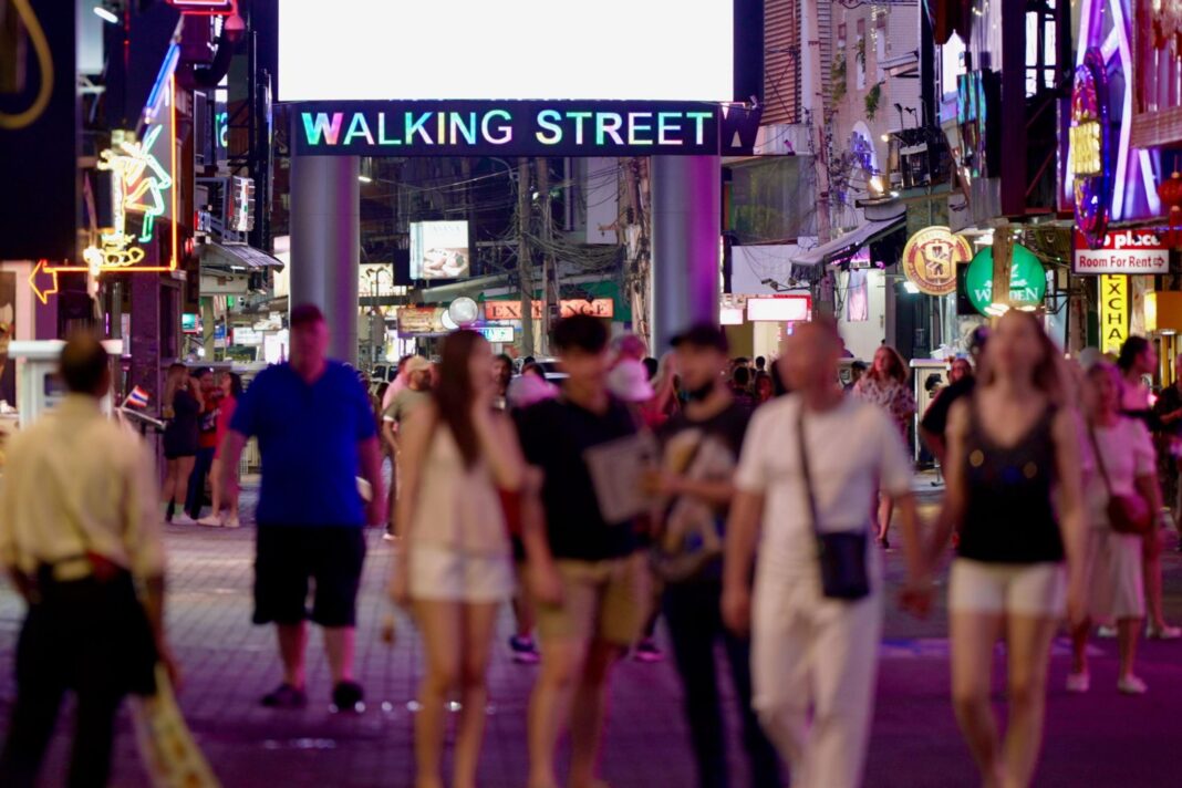 People walk along a street lined with bars and entertainment venues in Pattaya