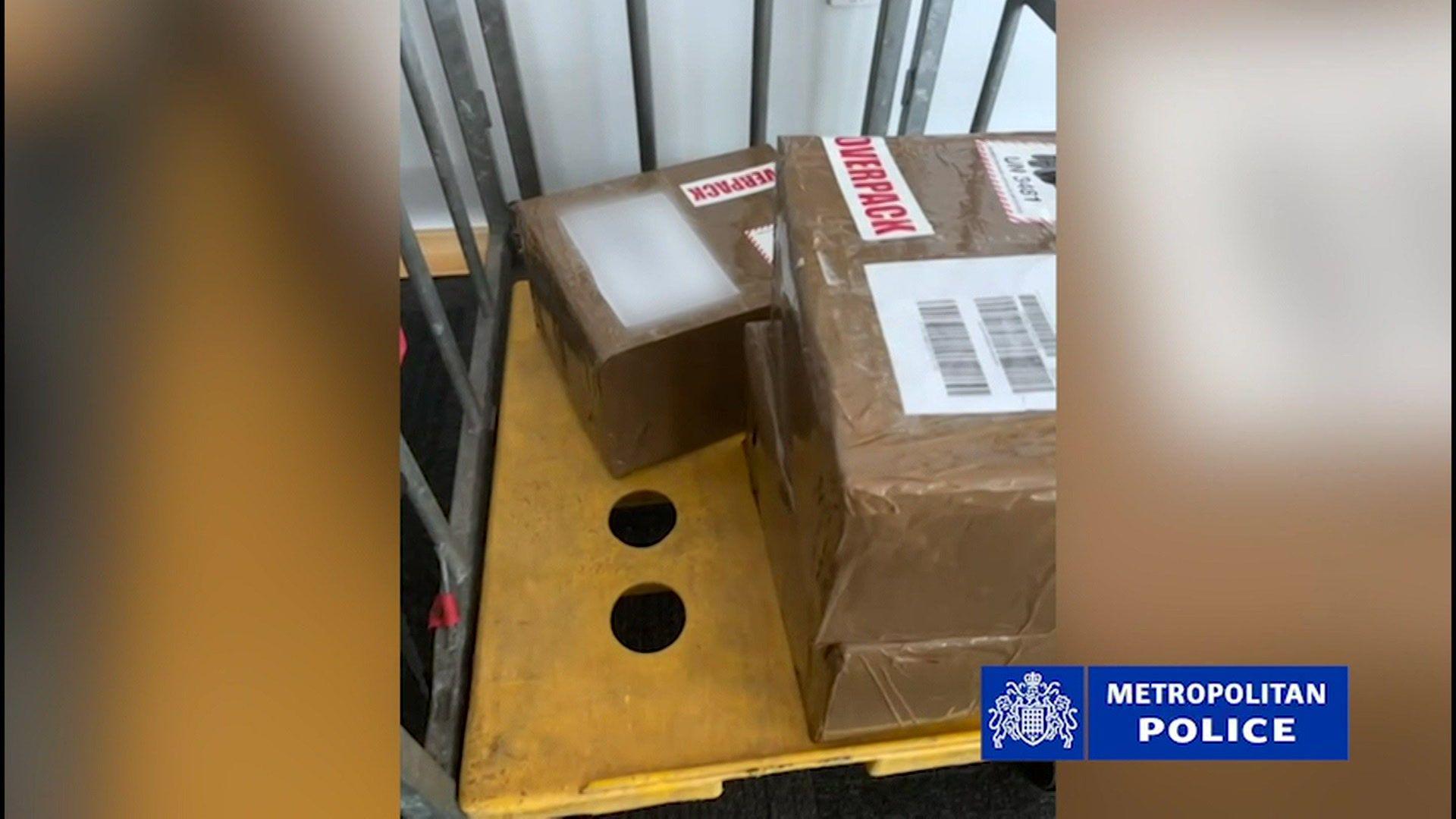 Three parcels, covered in brown masking tape and labels, are piled on a trolley