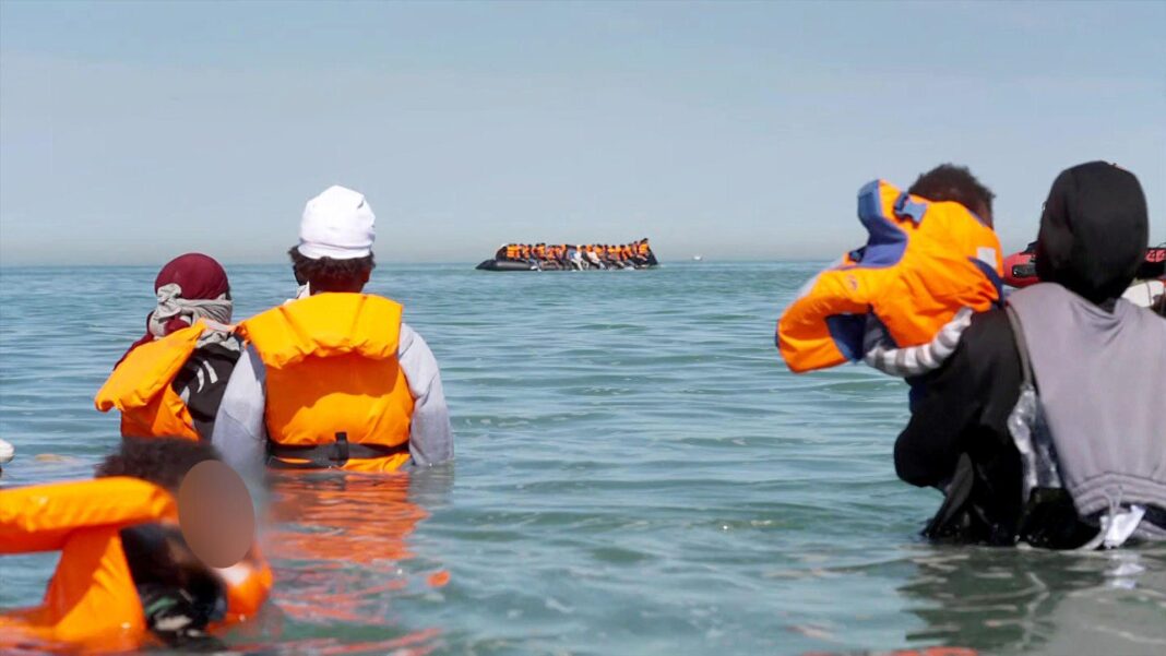 Migrants board an inflatable dinghy off the coast in France.