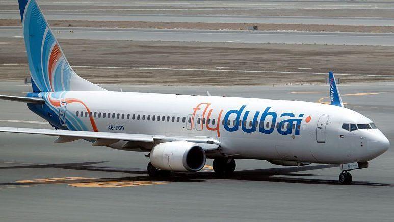 A file photo of a FlyDubai plane, white with orange and blue lettering, on a runway.