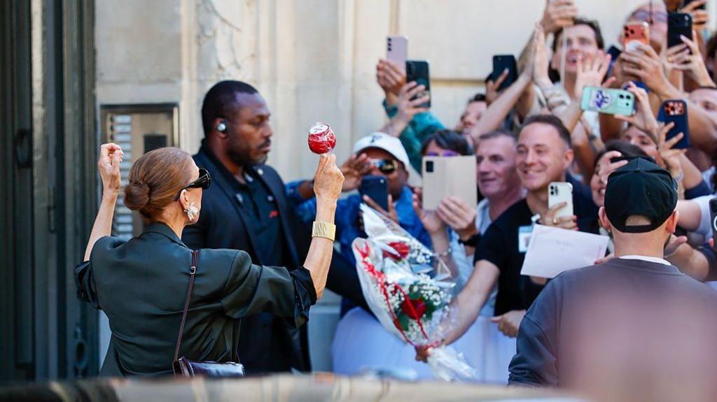 The singer meets fans outside her hotel, with one giving her flowers