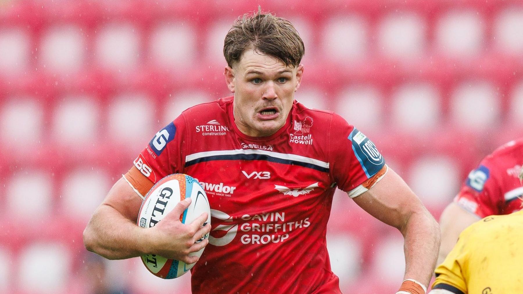 Taine Plumtree carries the ball under his right arm for Scarlets