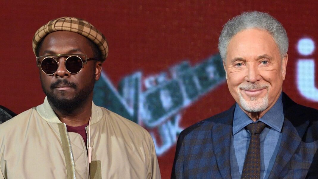 Will.i.am backs campaign for Sir Tom Jones to return to The Voice Will.I.Am stands next to Tom Jones, Will.I.Am is wearing a checked hat, sunglasses and a beige jacket. Tom Jones is wearing a blue shirt and checked jacket with a checked tie.