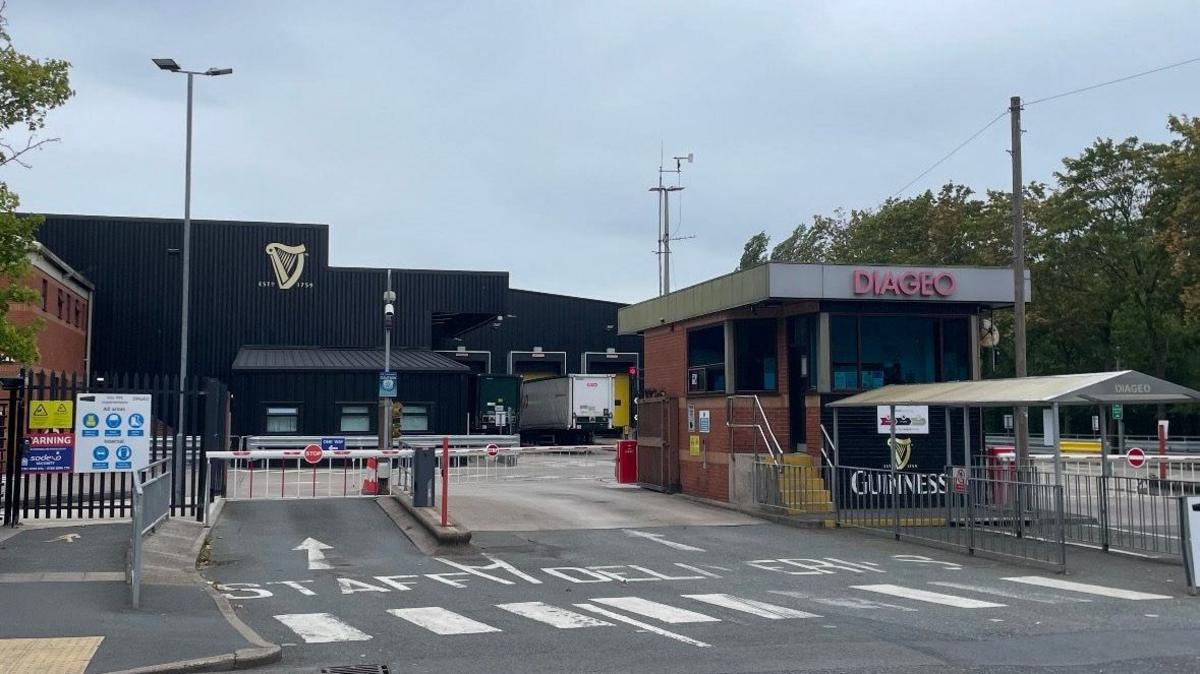 The entrance to the Diageo Packaging on Whitehouse Industrial Estate in Runcorn. There is a red and white barrier for vehicles at the entrance.